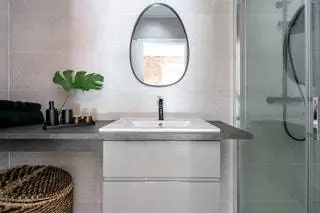 В ванных комнатах мы выбрали керамогранит среднего формата с отделкой под камень, чередование кремовых и серых тонов…