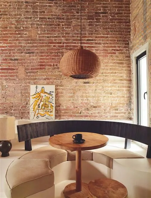 Гостиная с кирпичной стеной и круглой скамейкой на заказ с круглым центральным столом. Абстрактная живопись, опирающаяся на…