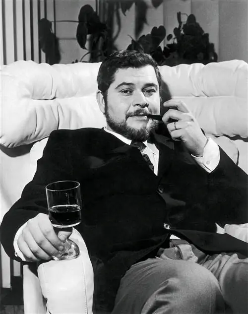 На изображении может находиться Joe Cesare Colombo Мебель Диван Одежда Одежда Человек Лицо Стекло Напитки и алкоголь