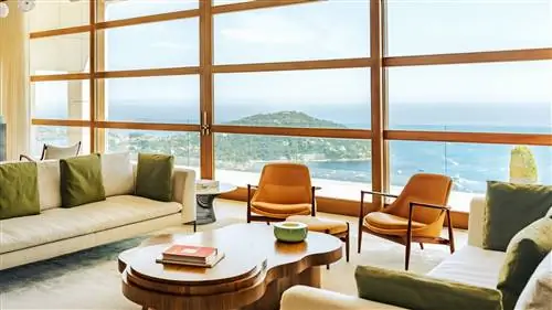 гостиная с большими окнами, белыми диванами и коричневыми креслами