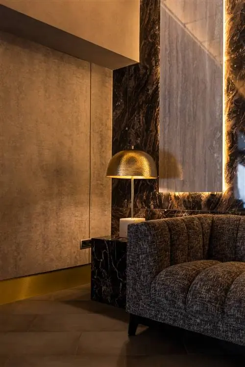 Дизайн клиники в темных тонах с золотым светильником и серым диваном