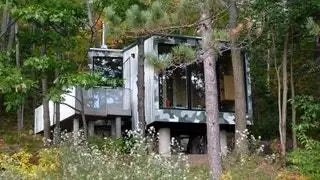 Это здание-спутник соседней большой хижины обращено к озеру и расположено на скалистой поверхности…