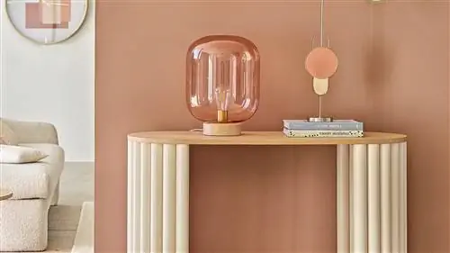 розовая стена с деревянным буфетом и кремовым диваном на заднем плане