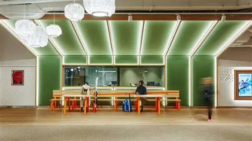 интерьер с деревянным полом зеленые панели на стенах в обрамлении дерева и подсветки. Деревянные столы и скамейки и…