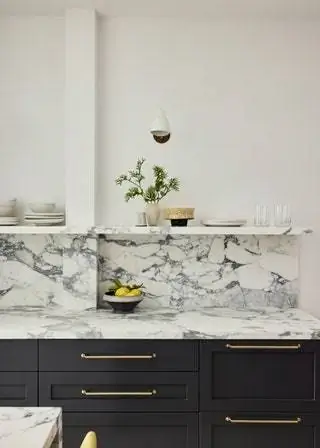 Обратите внимание на столешницу с золотыми ручками, мраморный фартук и темные тумбы с открытыми полками наверху в…