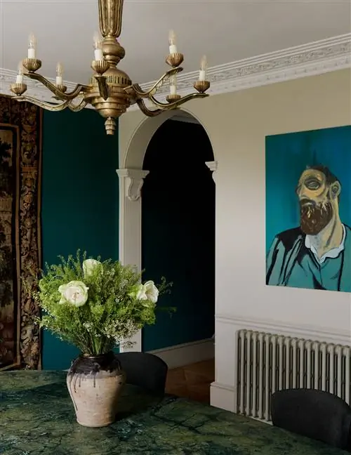 стол с вазой и цветами на стене и золотой подвесной светильник